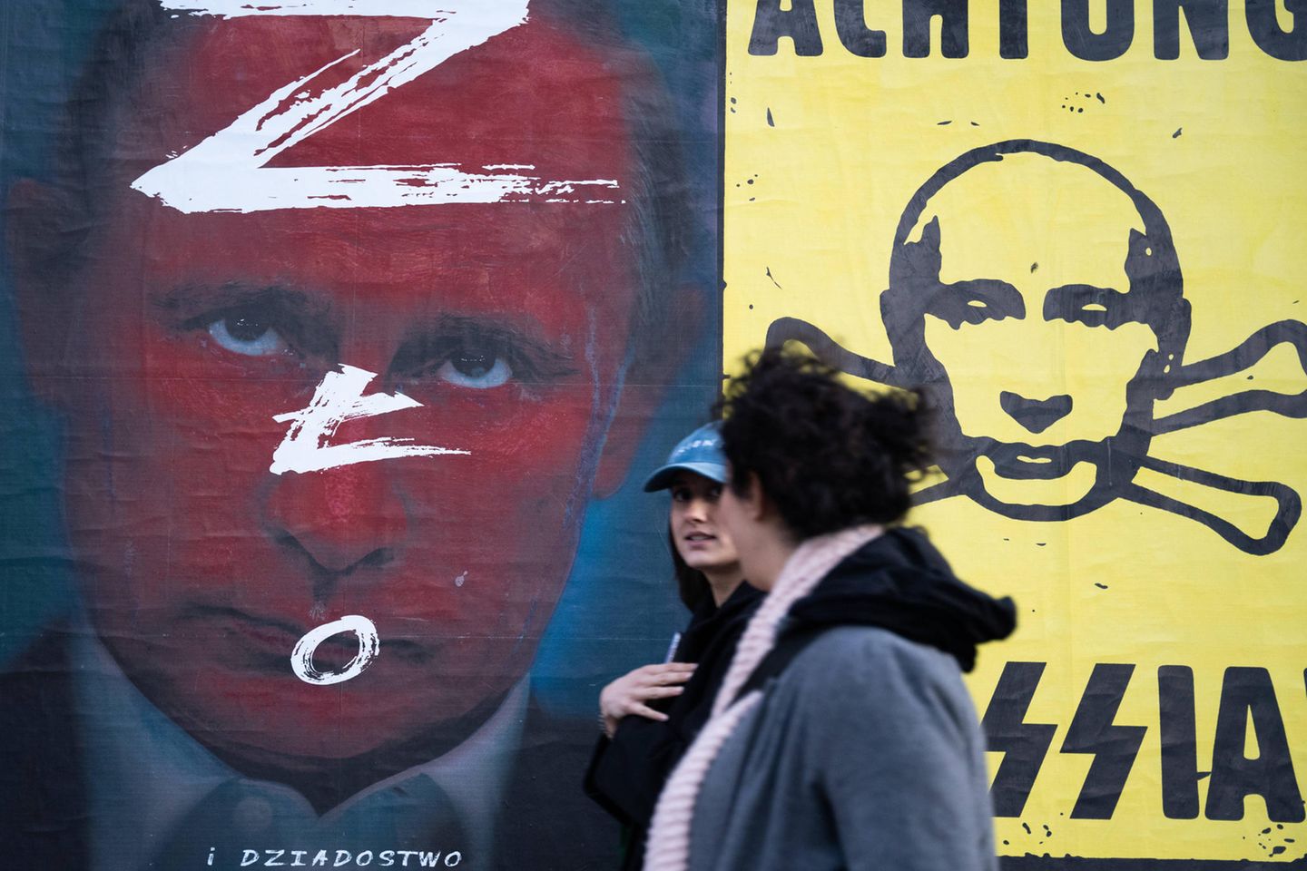 Menschen gehen an Anti-Putin-Postern in Warschau, Polen, vorbei.
