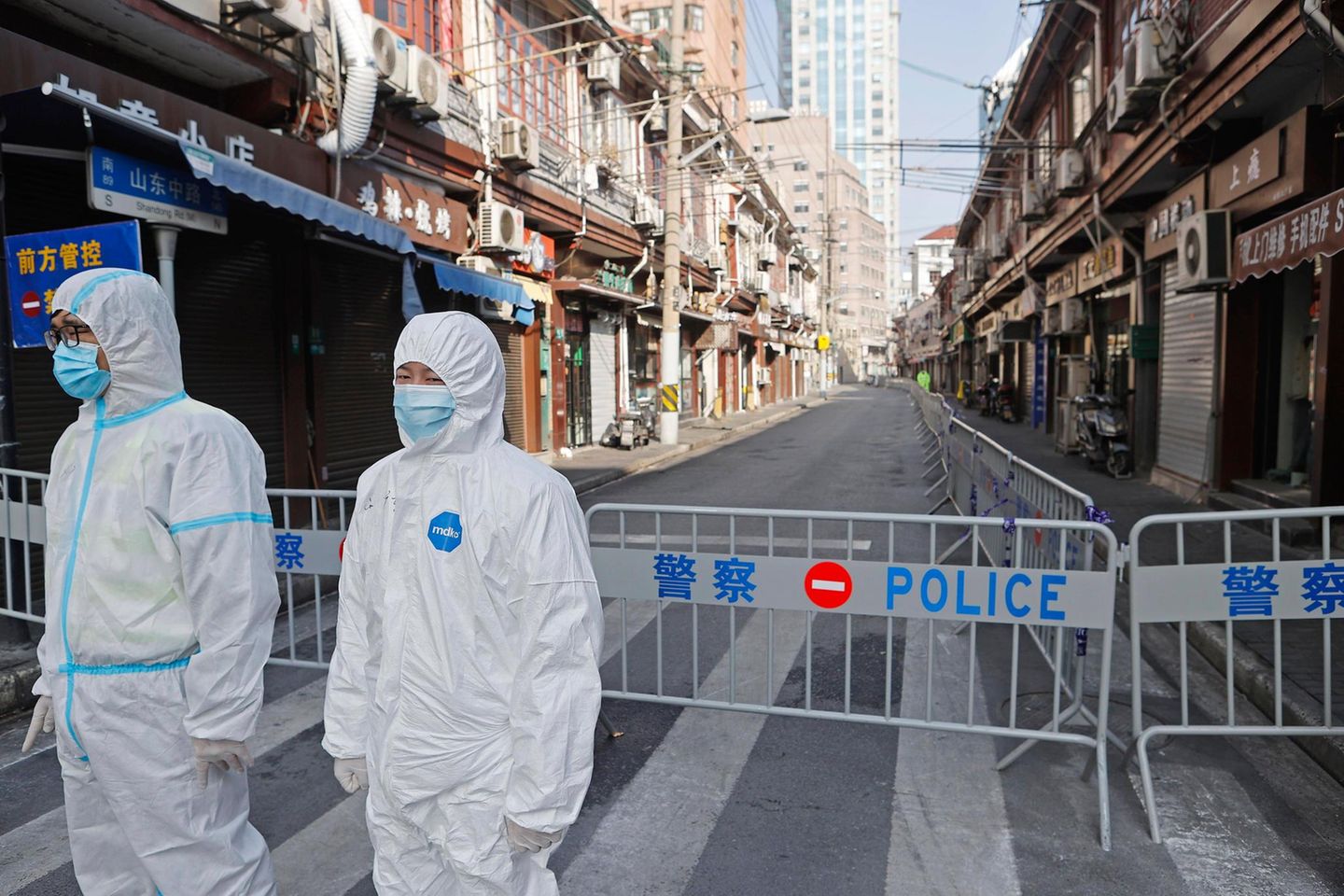Polizisten in Schutzkleidung bewachen ein Wohnviertel in Schanghai