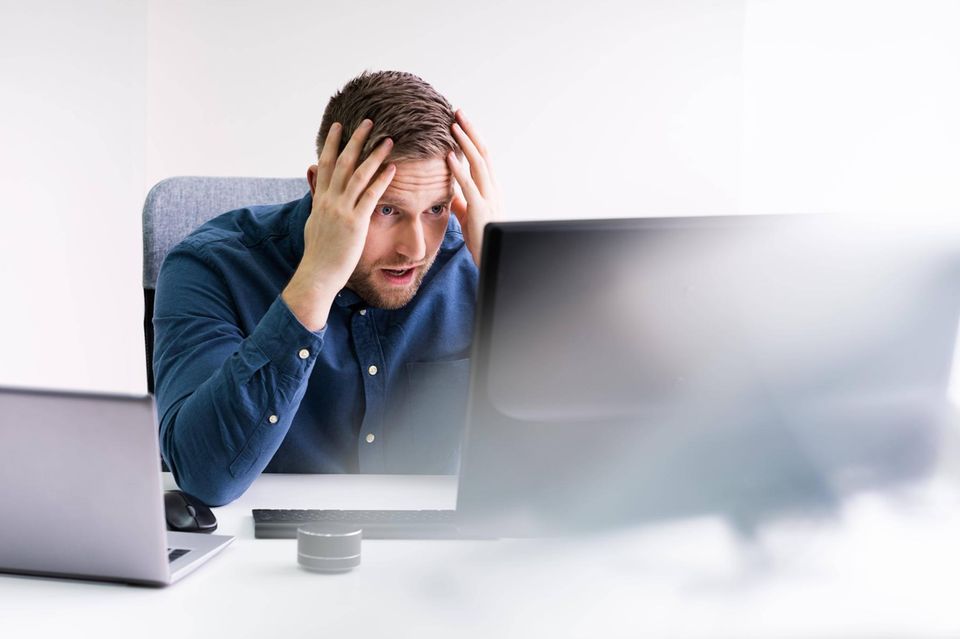 Ein Mann sitzt vor seinem Computer und rauft sich die Haare