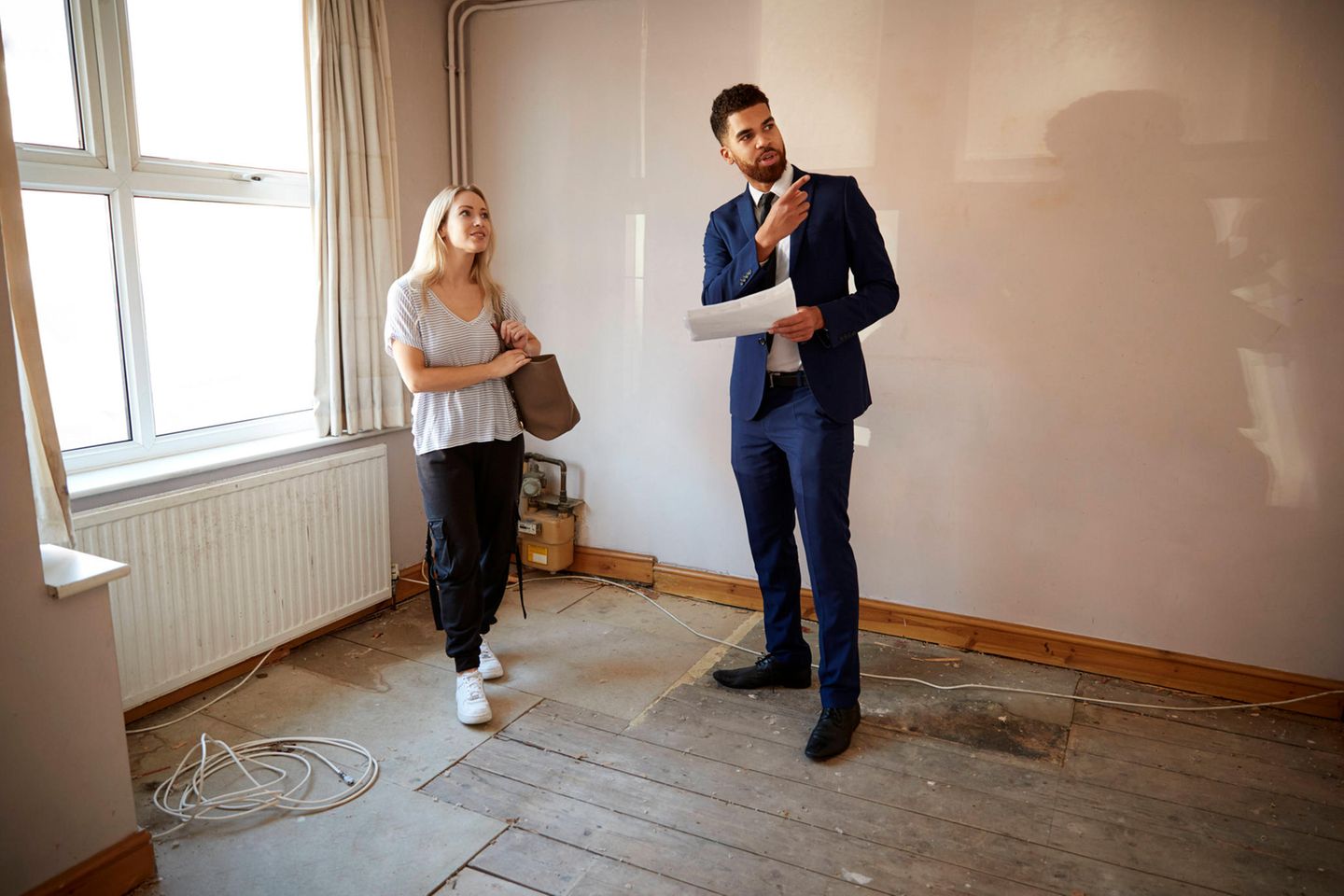 Ein Immobilienmakler zeigt einer Frau eine Wohnung