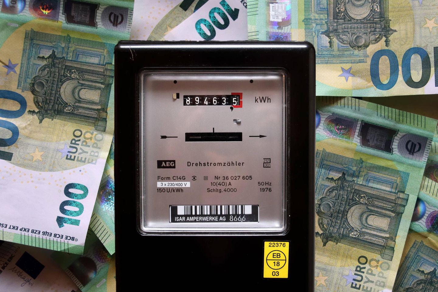 Ein Stromzähler mit Geldscheinen im Hintergrund