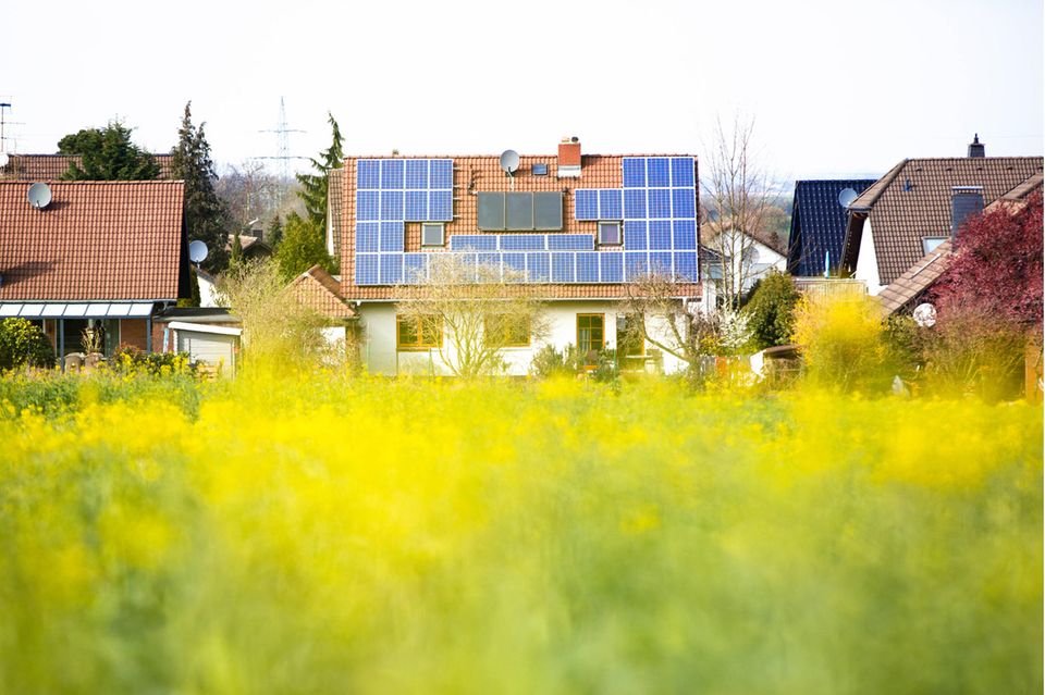 Photovoltaikanlage und thermische Solaranlage auf dem Dach eines am Ortsrand gelegenen Einfamilienhauses