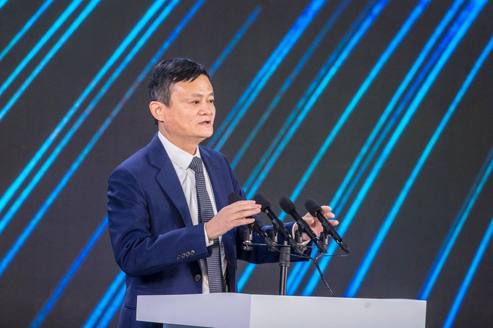 Jack Ma steht hinter einem Podium, auf dem mehrere Mikrofone angebracht sind