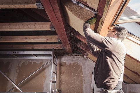 Ein Handwerker dämmt ein Hausdach