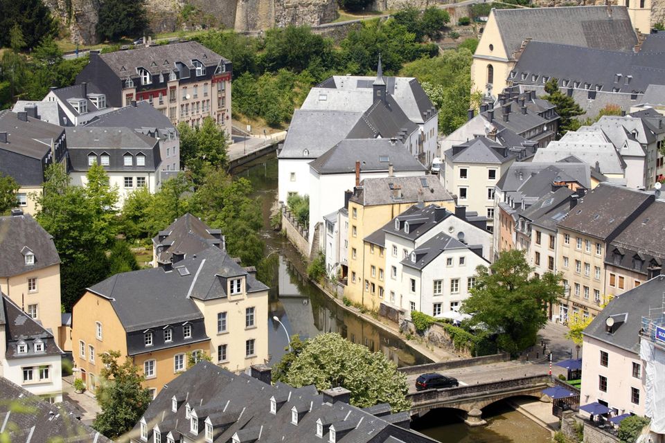 Ein Wohnviertel in Luxemburg. Durch die weißen und gelben Häuser schlängelt sich ein Fluss.