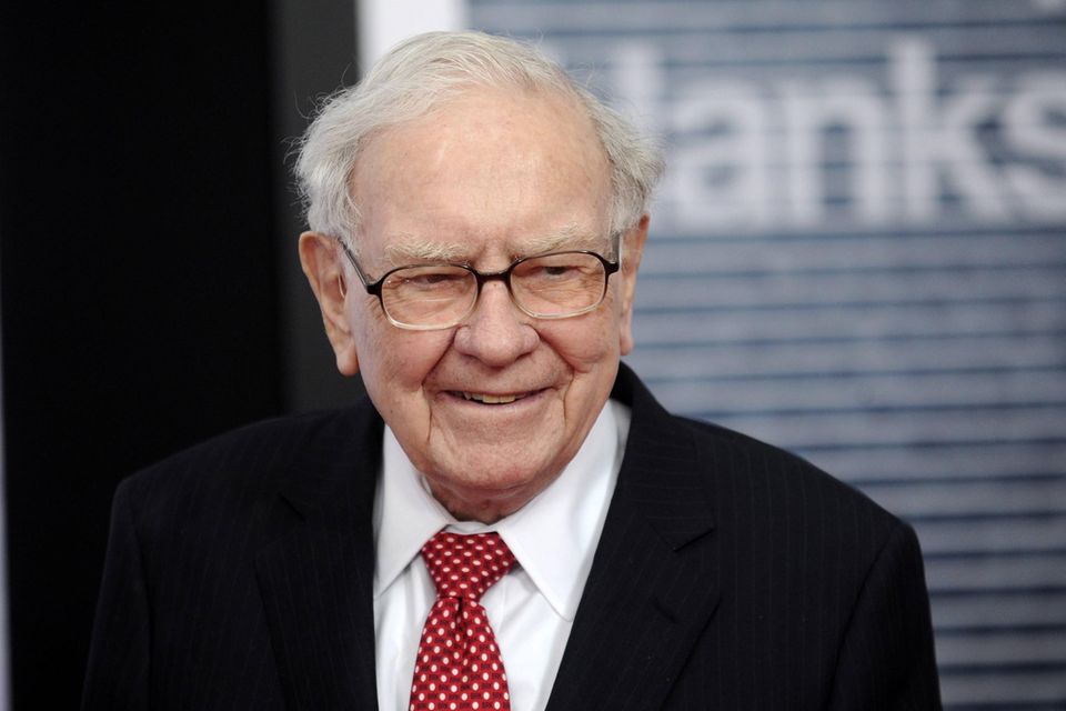 Warren Buffett mit Brille im schwarzen Anzug mit weißem Hemd und roter Krawatte mit weißen Punkten