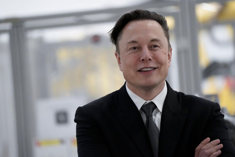 Elon Musk in schwarzem Jackett, weißem Hemd und mit schwarzer Krawatte.