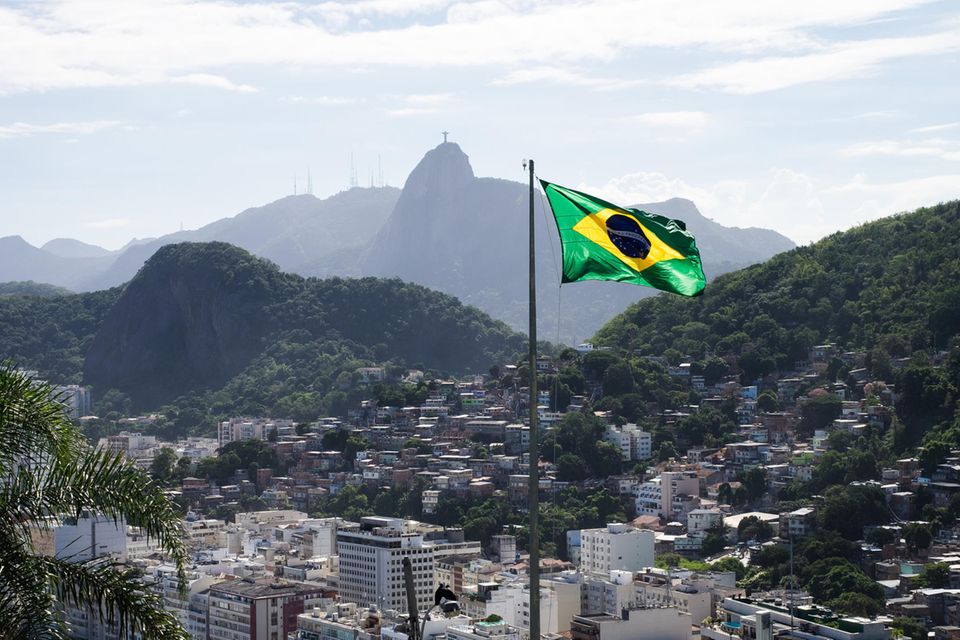 Die brasilianische Flagge vor dem Hintergrund einer Stadt in den Bergen