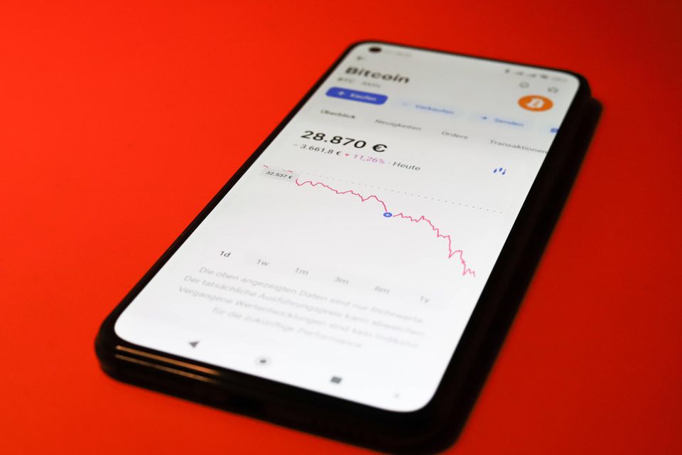 Symbolbild des fallenden Bitcoin-Kurses in einer Trading-App auf einem Smartphone