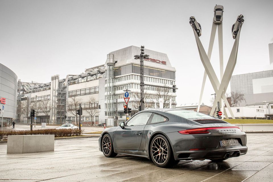 Porsche SE Vor der Porsche-Zentrale ragen drei Streben in die Luft, an deren Spitzen Autos angebracht sind