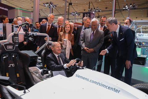 Bundeskanzler Scholz sitzt am Stand der Firma Siemens in einem vollelektrischen Fahrzeug