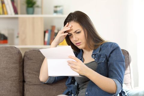 Eine besorgt aussehende Frau liest einen Brief
