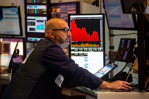Ein Aktienhändler sitzt an seinem Arbeitsplatz an der New Yorker Börse und schaut auf einen Monitor