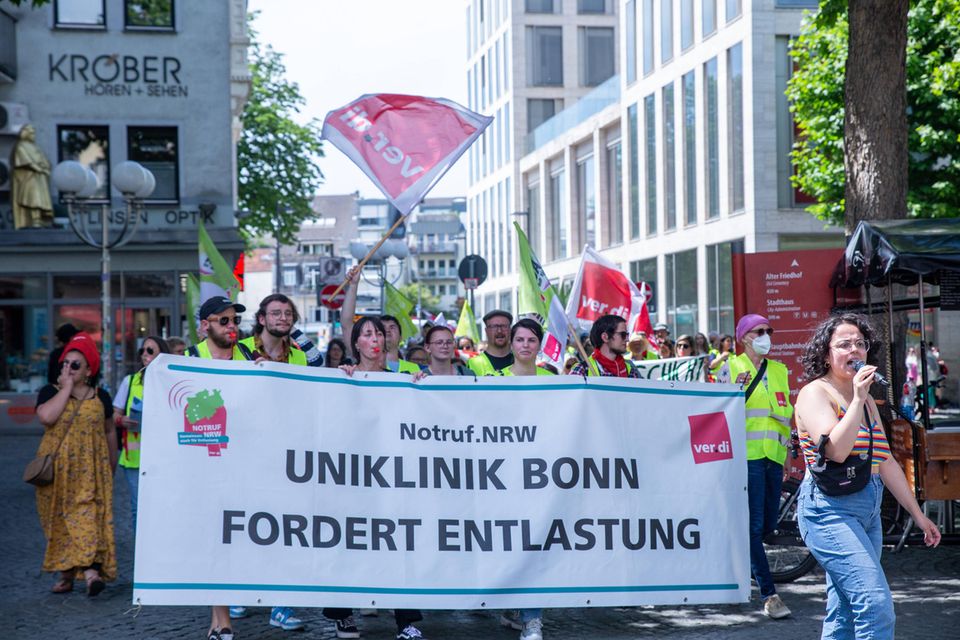 Streikende ziehen durch die Straßen; tagen Banner vor sich her und schwenken Flaggen