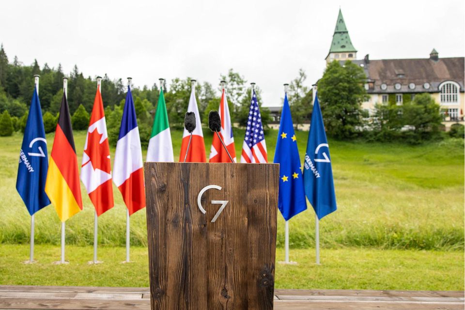 Ein Pult mit dem Symbol der G7 und den Flaggen der Mitgliedsstaaten im Hintergrund