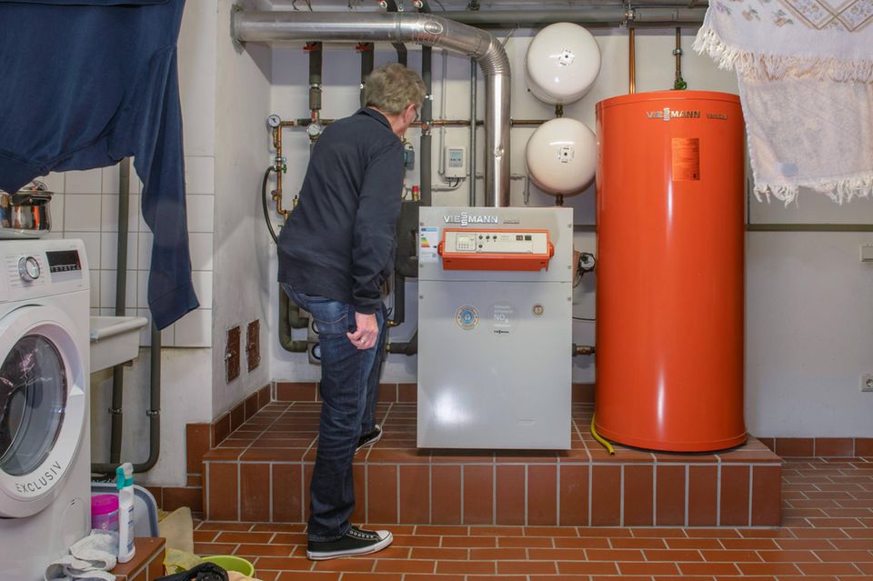 Ein Mann steht vor einer Gasheizung im Keller eines Hauses