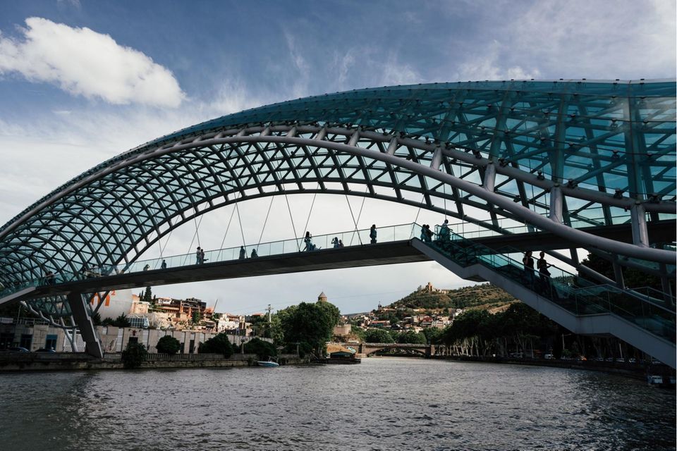 Touristen spazieren über die Friedensbrücke in Tiflis