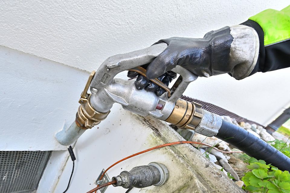 Der Öltank eines Hauses wird mit einer Zapfpistole betankt