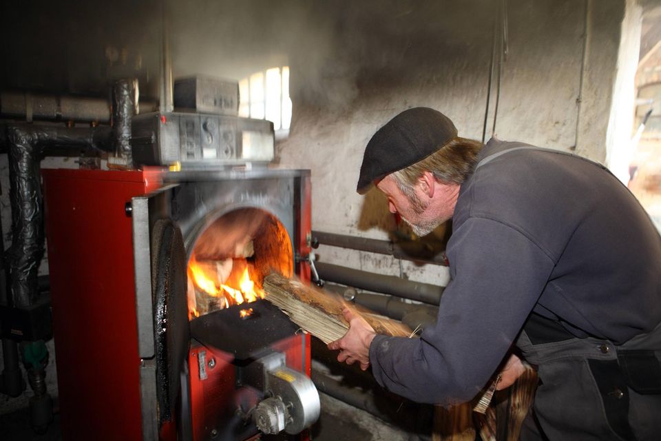 Ein Mann füllt einen Holzvergaserofen mit Brennholz