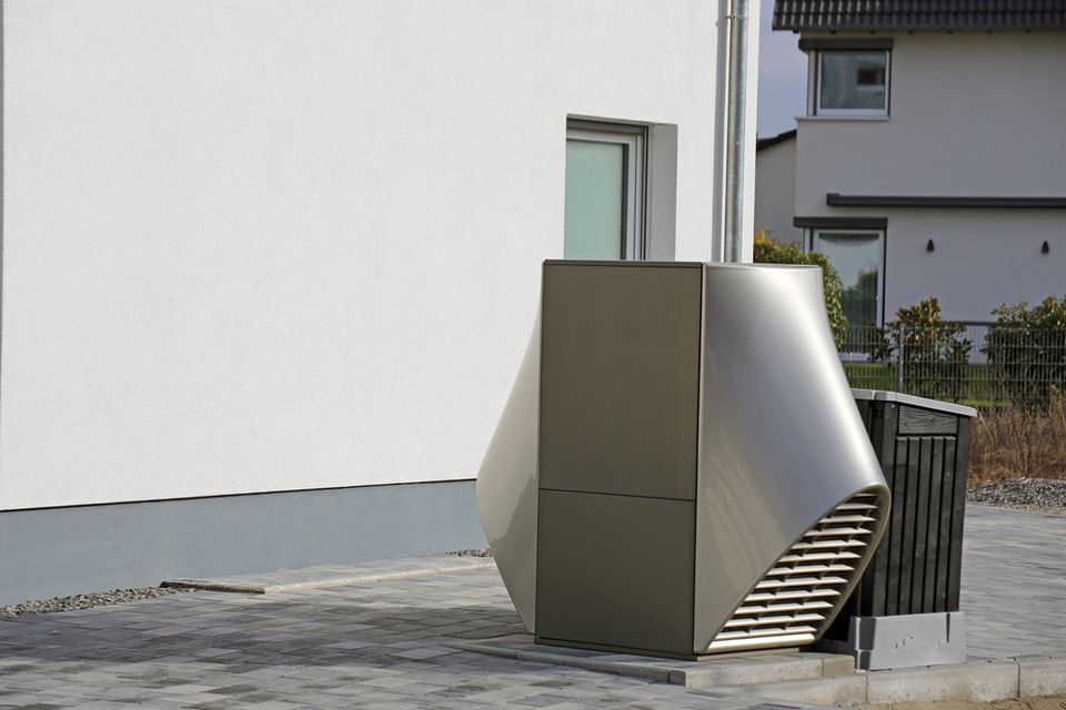 Eine Luftwärmepumpe steht vor einem neuen Wohnhaus