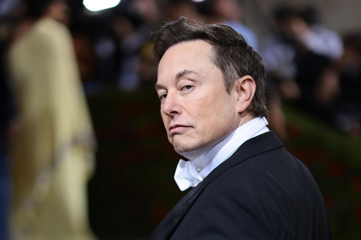 Elon Musk blickt über die Schulter in die Kamera