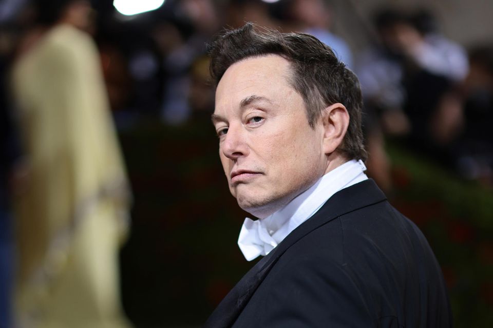 Elon Musk blickt über die Schulter in die Kamera