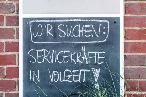 Auf einem Schild an einer Hauswand steht: "Wir suchen Servicekräfte in Vollzeit"