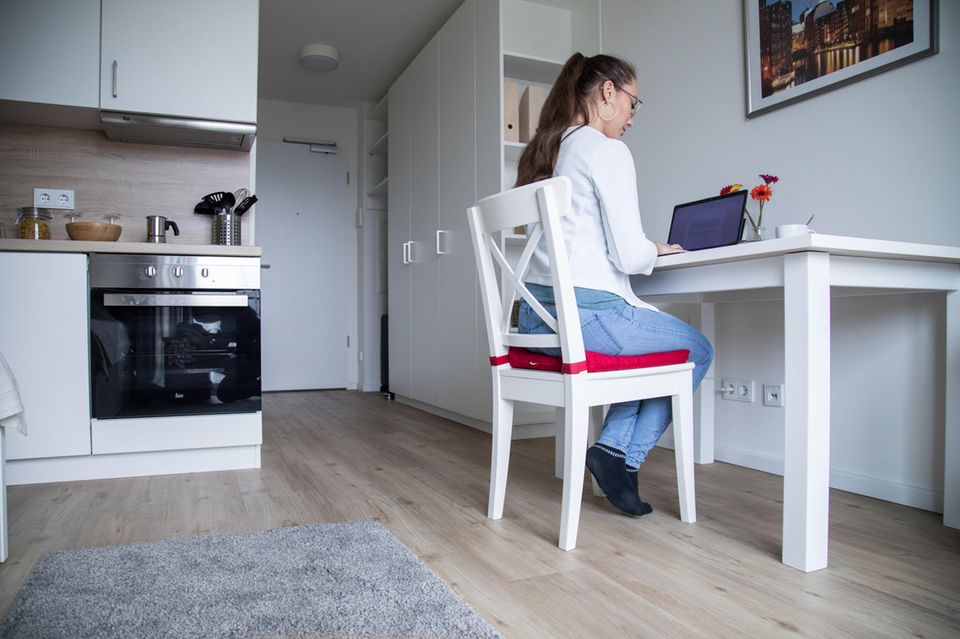Eine Frau arbeitet in ihrer Einzimmerwohnung an einem Notebook