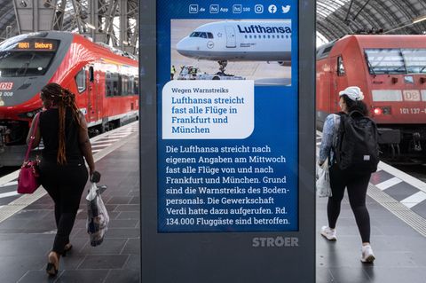 Bahnreisende gehen an einem Infobildschirm im Frankfurter Hauptbahnhof vorbei