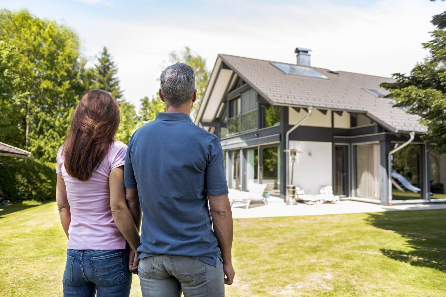 Eine Frau und ein Mann stehen im Garten eines Einfamilienhauses