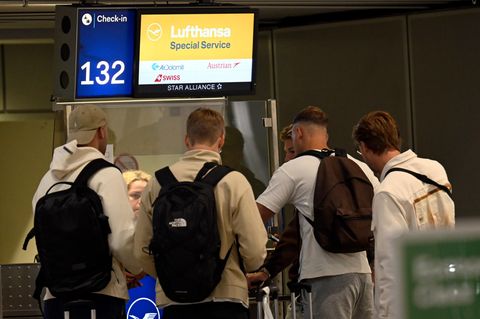 Reisende stehen vor einem Lufthansa-Schalter im Terminal