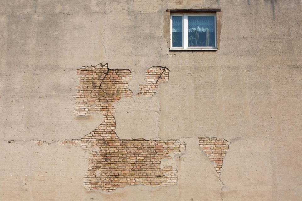 Fassade und Fenster eines alten, sanierungsbedürftigen Wohnhauses