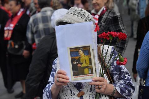 Eine Frau hat Blumen und ein Bild von Stalin in der Hand