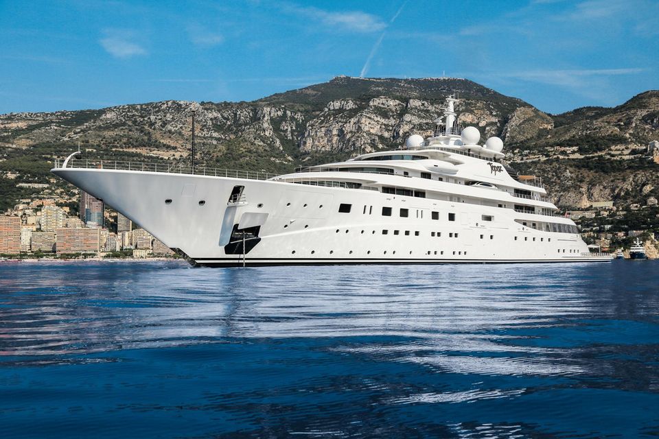 Die riesige weiße Luxus-Yacht mit Bergen im Hintergrund