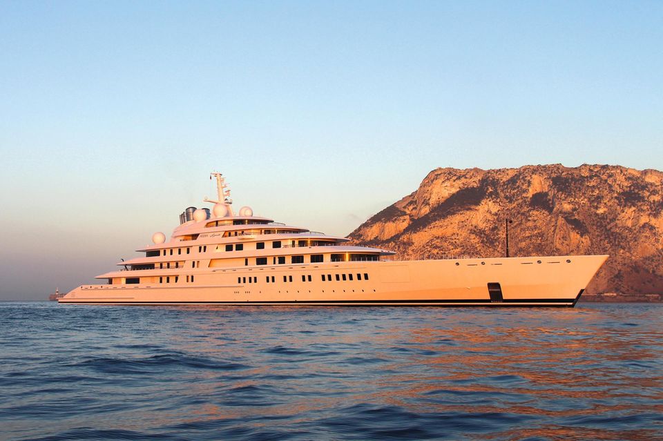 Die größte Yacht der Welt liegt im Sonnenuntergang vor einer gebirgigen Insel