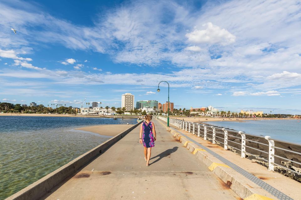 Eine Frau geht einen Pier entlang auf eine Stadt zu