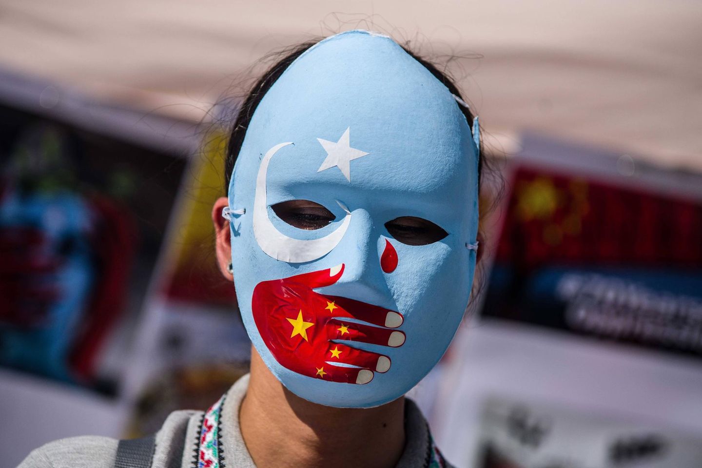 Eine Demonstrantin protestiert in München gegen den Umgang der chinesischen Regierung mit der uigurischen Minderheit, die mutmaßlich Zwangsarbeit verrichten müssen
