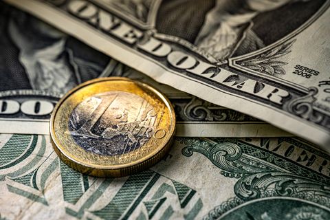 Eine Ein-Euro-Münze liegt auf mehreren Dollar-Scheinen