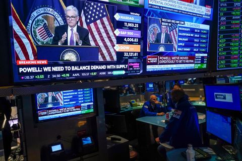 An der New Yorker Börse wird eine Pressekonferenz von Fed-Chef Jerome Powell gezeigt, während die Händler arbeiten und zusehen