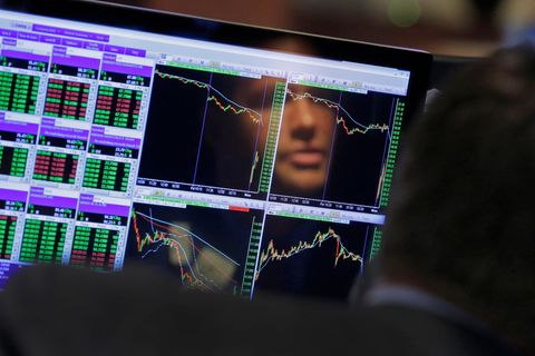 Das Gesicht eines Aktienhändlers spiegelt sich auf Monitoren mit Charts und Kursen