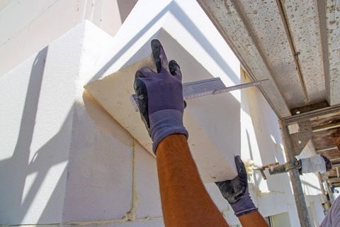 Bauarbeiter bringen Wärmeplatten an einer Fassade an 