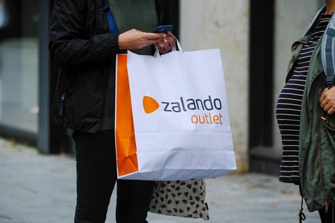 Eine Frau steht mit einer Zalando-Tüte auf einer Einkaufsstraße