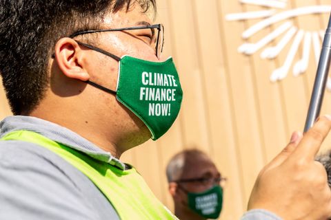 Demonstranten tragen Masken mit der Aufschrift "Climate Finance Now"
