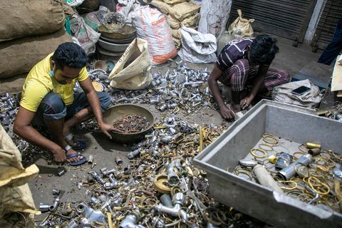 Zwei indische Arbeiter sortieren Metallschrott