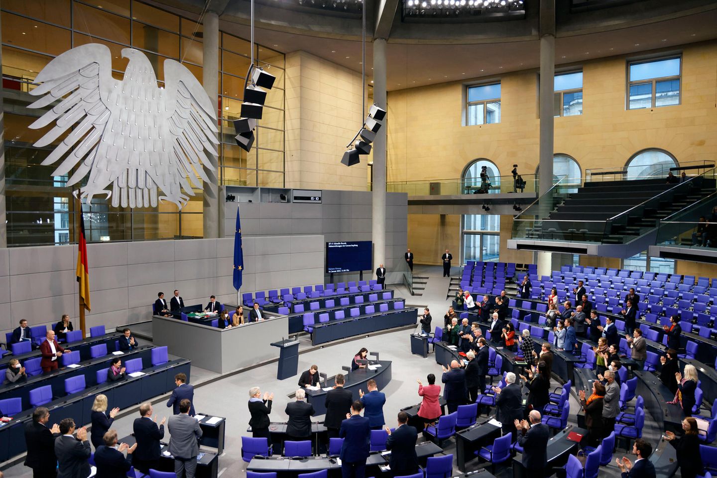 Blick in den Plenarsaal des Bundestags, wo Abgeordnete stehend applaudieren
