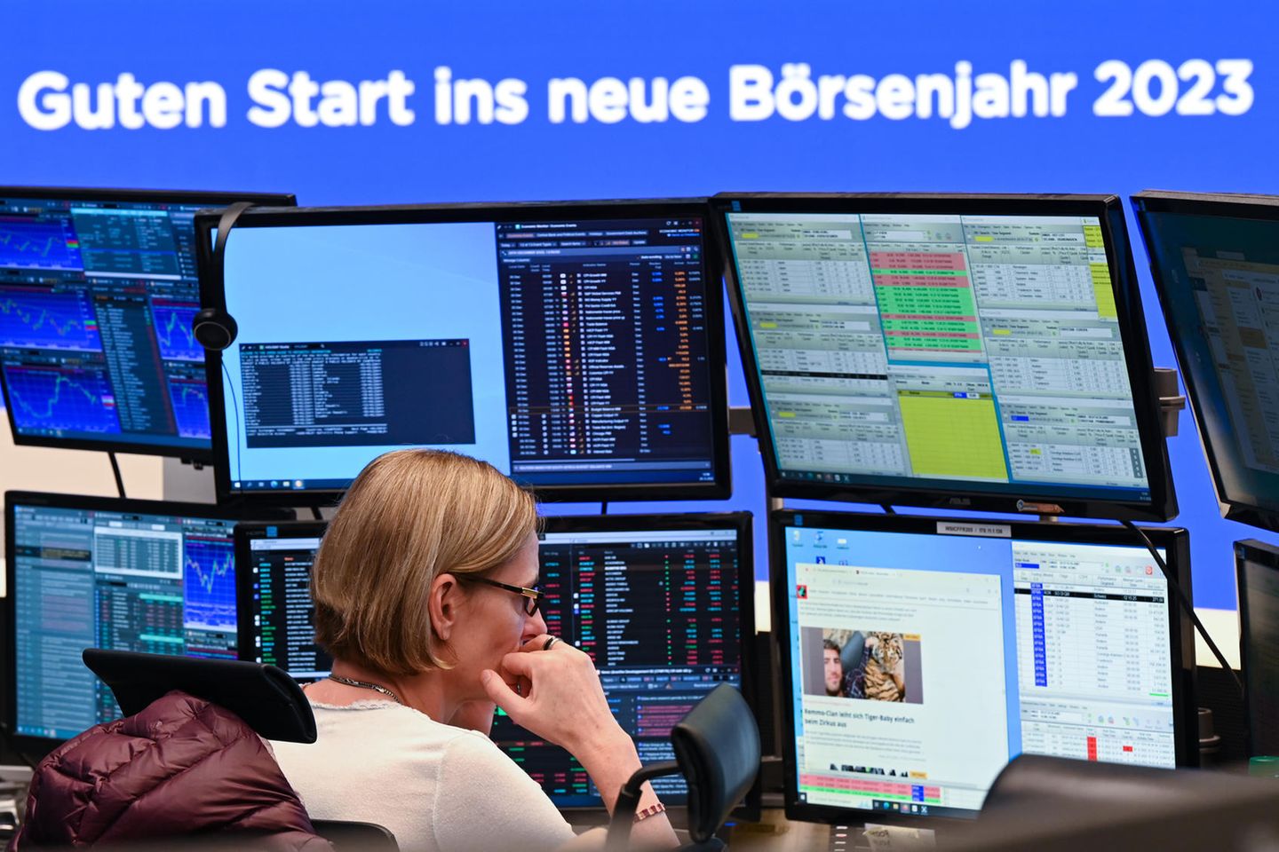 Eine Händlerin blickt an der Frankfurter Börse vor der Grußbotschaft „Guten Start ins neue Börsenjahr 2023“ auf ihre Monitore