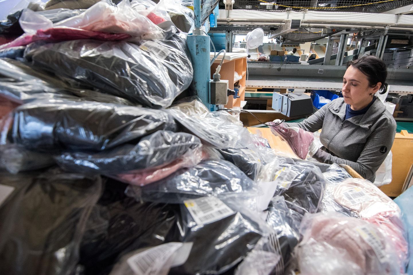 Eine Mitarbeiterin kontrolliert im Hermes Rücksendezentrum die Ware aus Retoure-Paketen