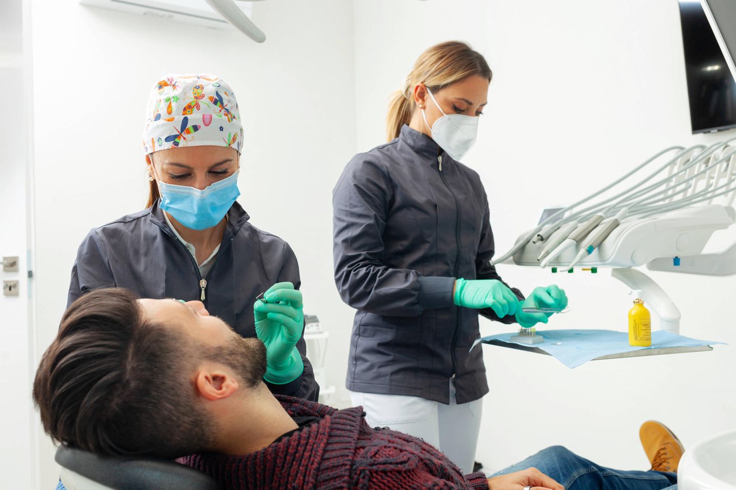 Eine Zahnärztin untersucht einen männlichen Patienten in einer Zahnarztpraxis