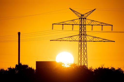 Die Sonne geht hinter einer Hochspannungsleitung an der Ems auf