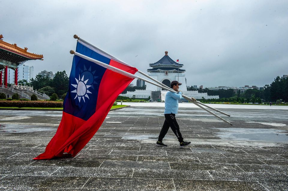 Ein Mann trägt Flaggen Taiwans über einen Platz